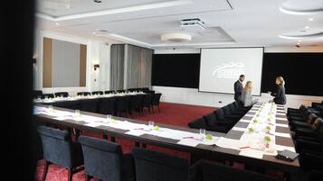 A conference room with a long table, chairs, a projector screen, and a presentation on the wall.