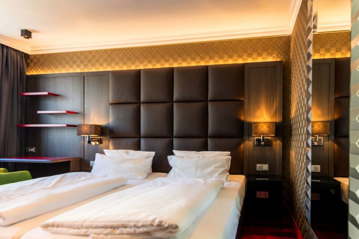 A hotel room with a large bed, bedside lamps, a desk, and a chair.