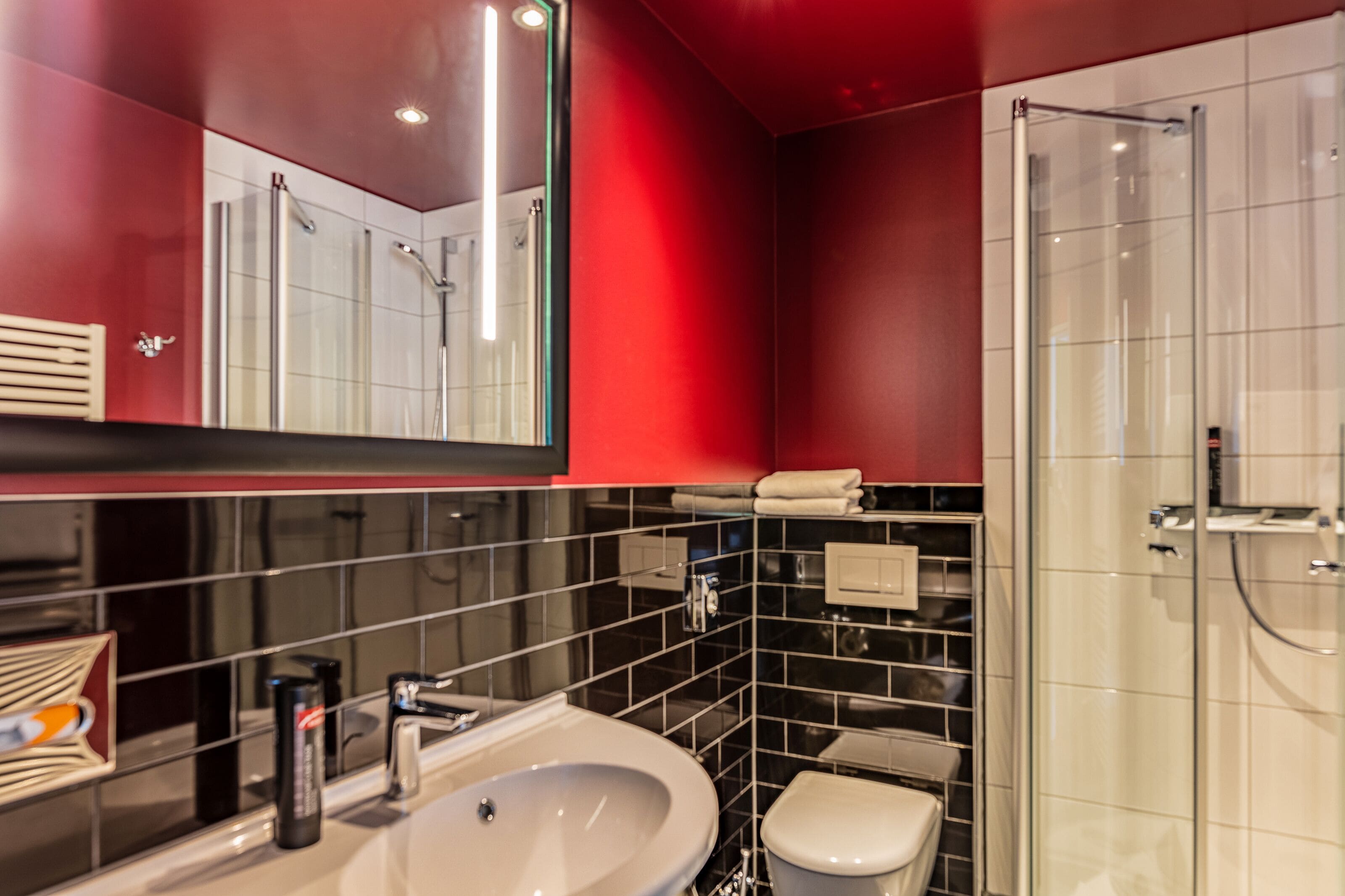 Ein modernes Badezimmer mit großem Spiegel, Waschbecken, Toilette und einer Duschkabine.