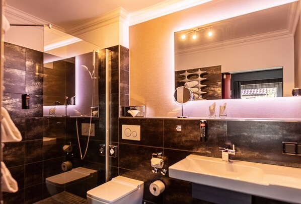 A modern bathroom with a large mirror, a shower, a toilet, and a sink. - Hotel Haverkamp (Bremerhaven)
