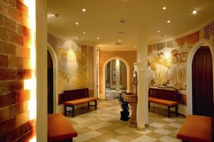 Un vestíbulo de hotel con piso de cuadros, bancos, una fuente y un mural.