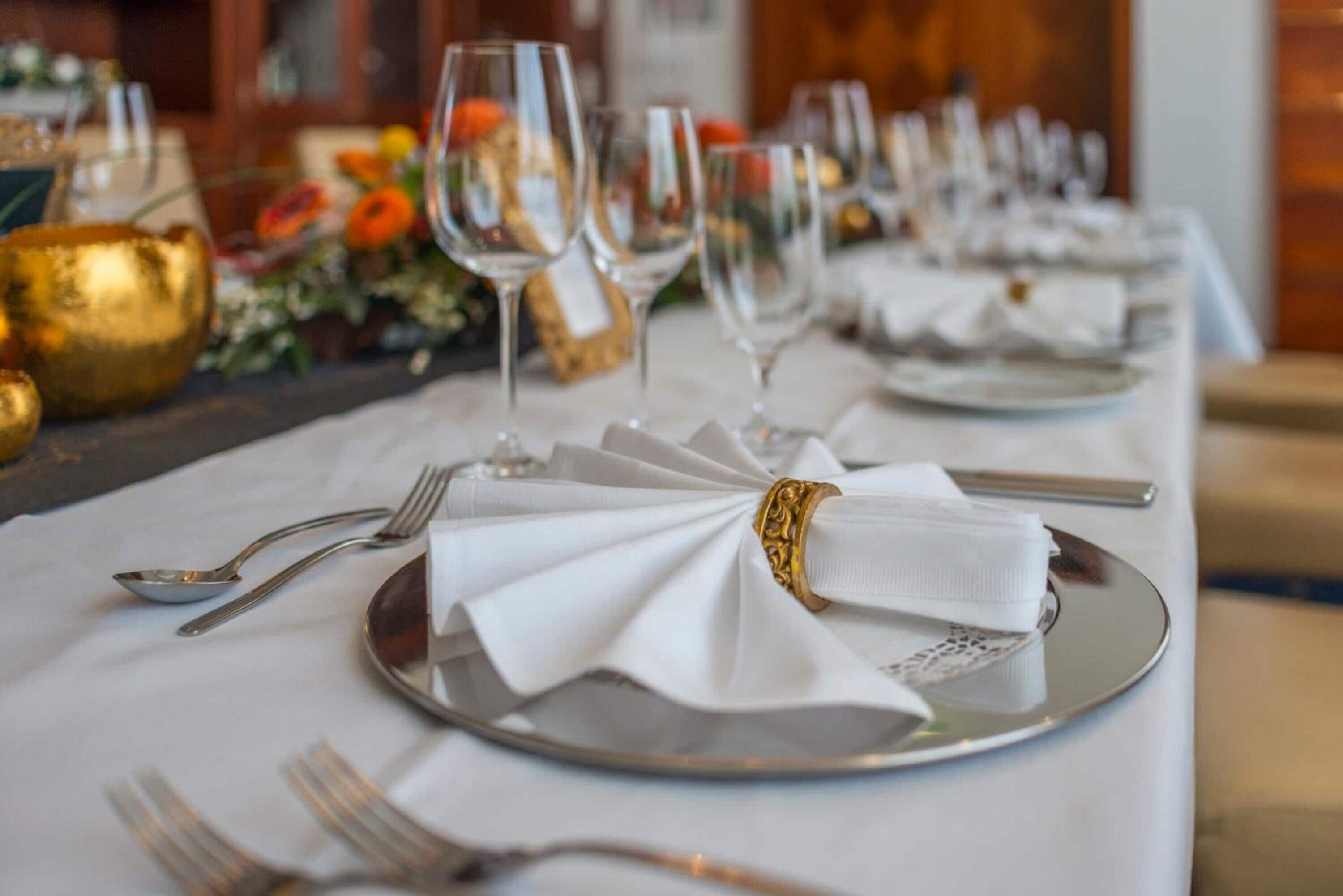 Ein Tisch ist festlich für ein formelles Essen gedeckt, mit weißen Servietten, Besteck und Weingläsern.