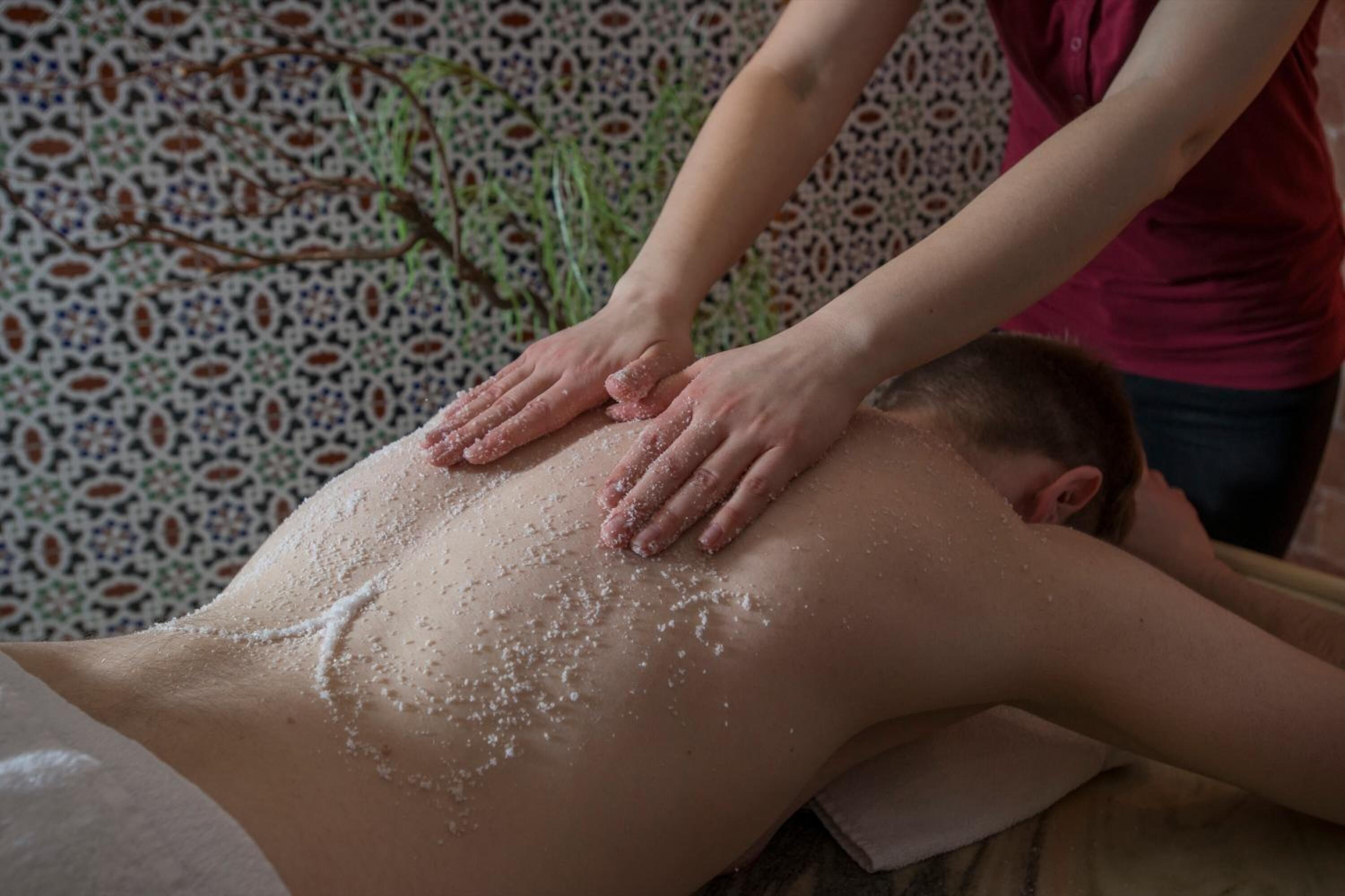 Eine Person erhält eine Massage, wobei Hände Druck auf den Rücken ausüben.