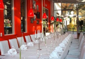A long table set for a formal event with white chairs and table settings. - Hotel Glöcklhofer (Burghausen)