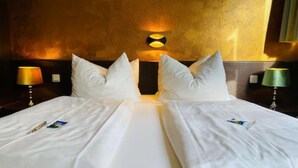 A hotel room with a large bed, two pillows, and two bedside lamps. - Hotel Christina (Cologne)