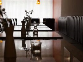 Uma sala de jantar moderna com mesa de vidro, cadeiras e um vaso de planta.