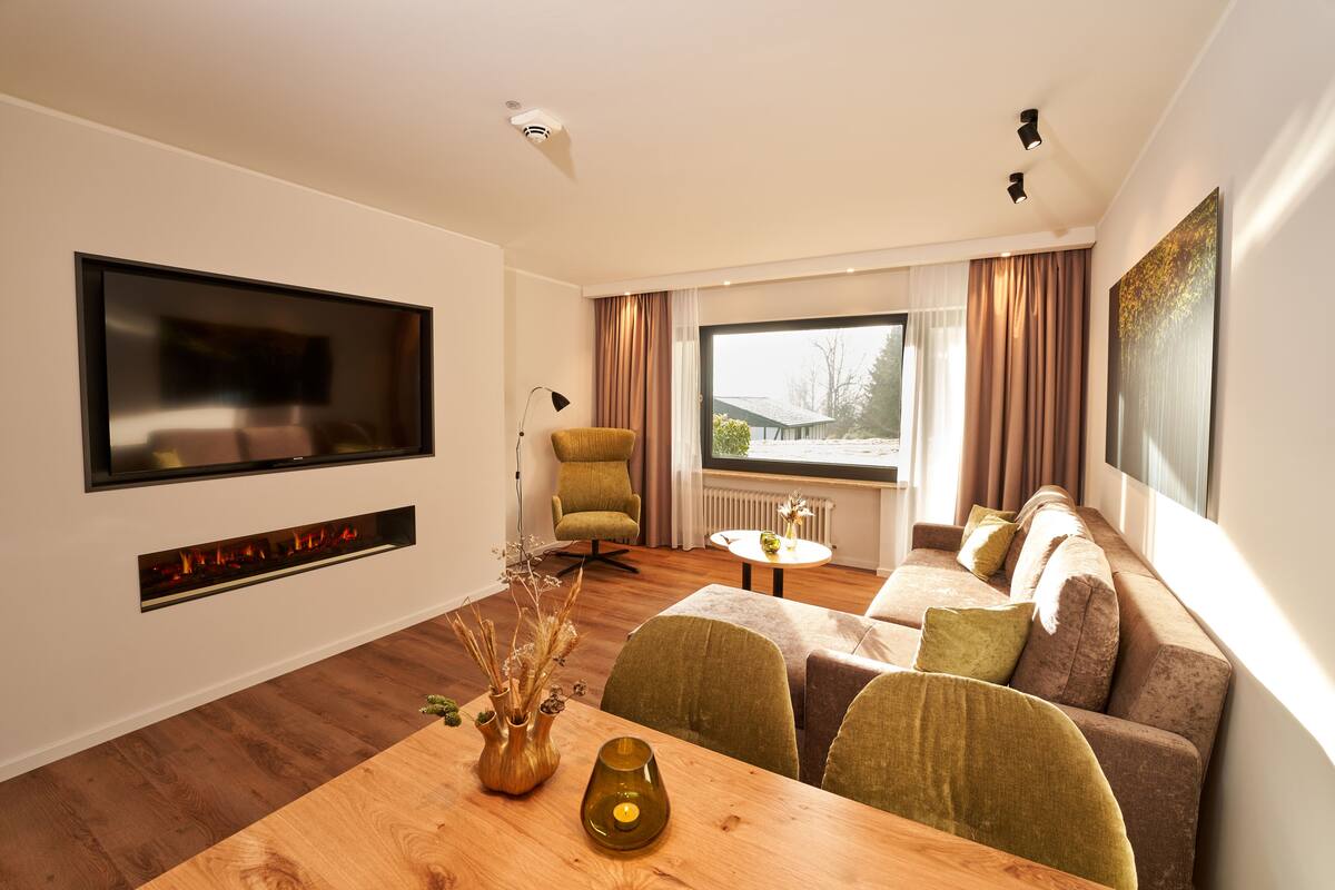 A modern living room with a flat-screen TV, a fireplace, a sofa, and a dining table.