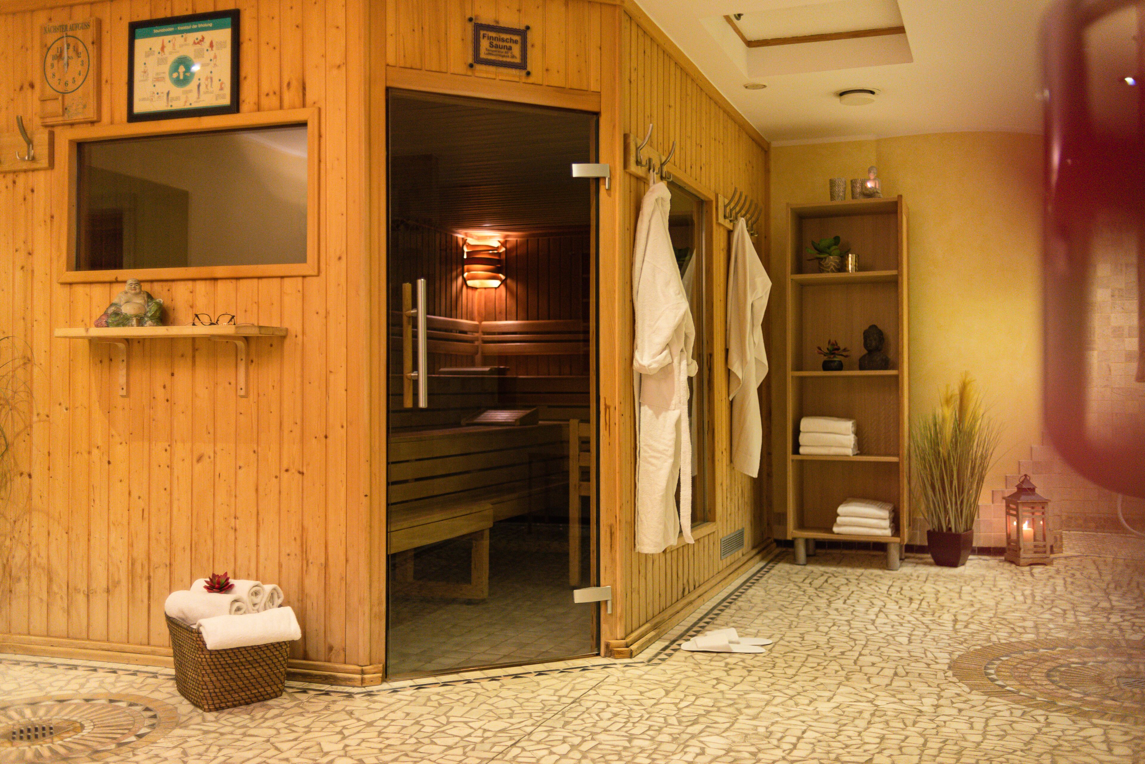 Una sauna de madera con bancos, toallas y un estante con artículos de aseo.