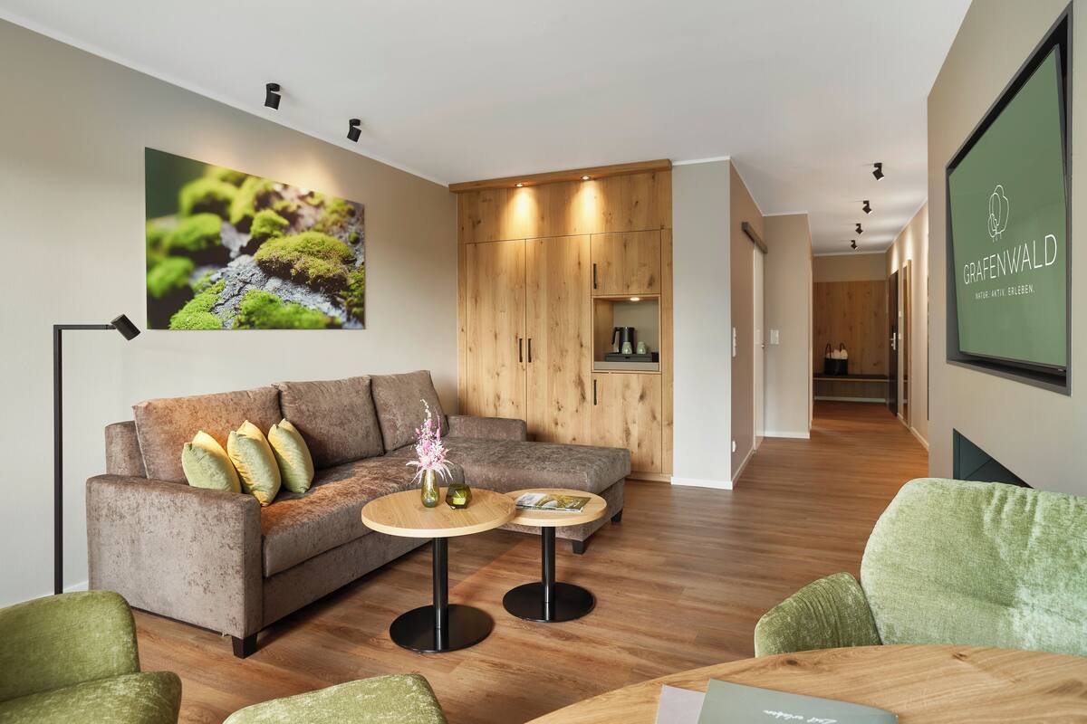 A modern living room with a sofa, two round tables, and a wooden cabinet.