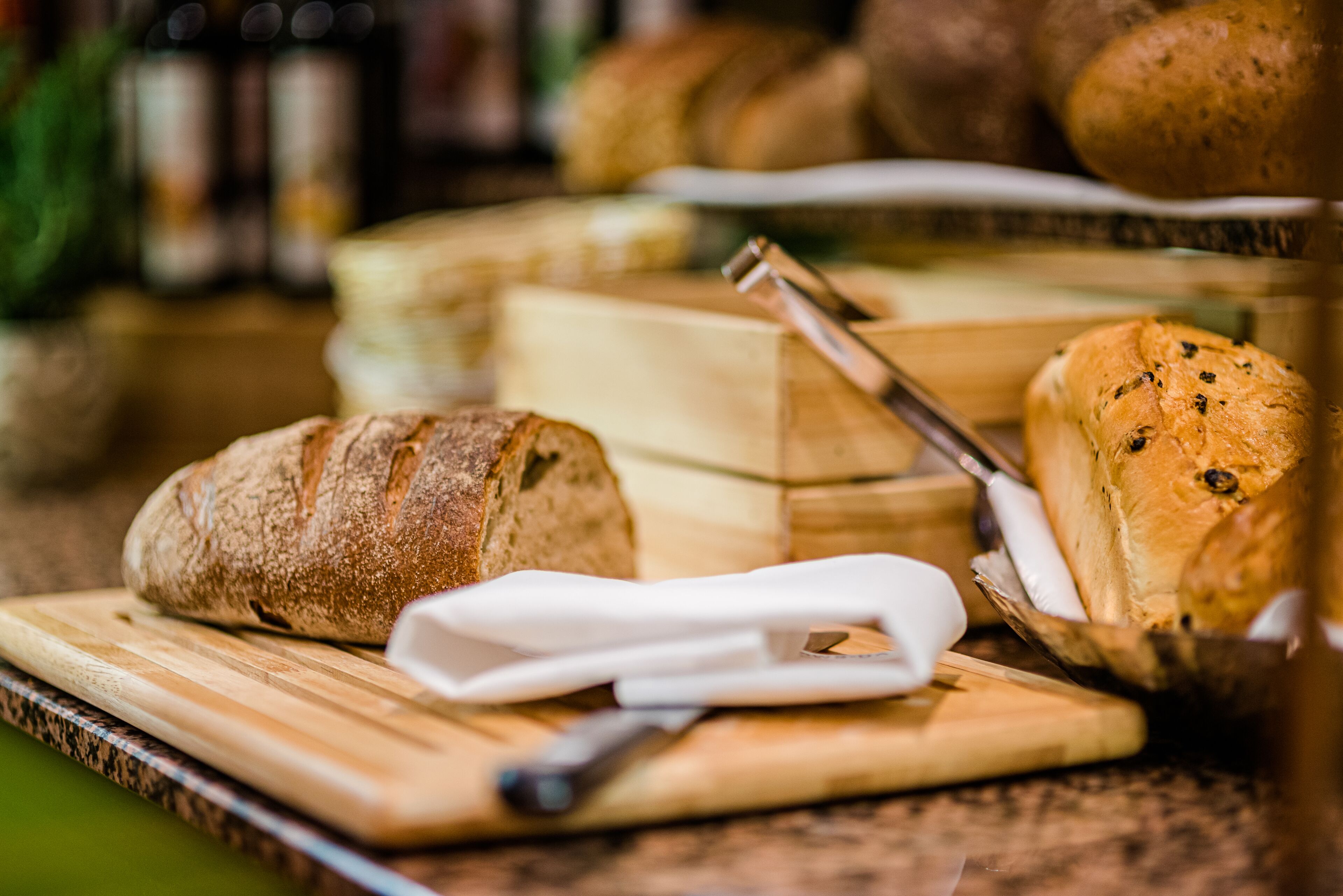 Una tabla de madera con una hogaza de pan, un cuchillo y una cesta con pan.
