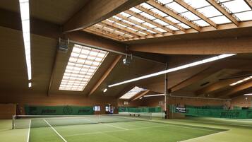 An indoor tennis court with a high ceiling and skylights.