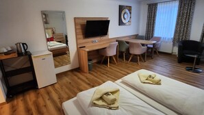 A hotel room with two beds, a desk, a chair, a television, and a window with curtains. - Posthotel Traube (Donauwoerth)
