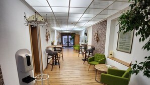 A hallway with a reception desk, seating area, and a plant. - Posthotel Traube (Donauwoerth)