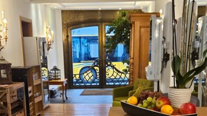 A wooden floor, a table with a fruit bowl, and a view of the outside through a glass door. - Posthotel Traube (Donauwoerth)