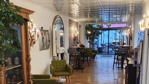 A hotel lobby with wooden flooring, green armchairs, a reception desk, and a large mirror. - Posthotel Traube (Donauwoerth)