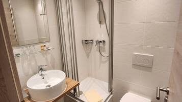 Ein modernes Badezimmer mit einer gläsernen Duschkabine, einem Waschbecken mit Holzablage und einer Toilette.