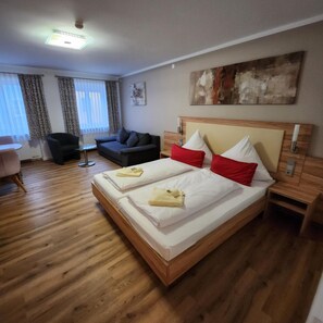 A hotel room with a large bed, a sofa, a coffee table, and a painting on the wall. - Posthotel Traube (Donauwoerth)