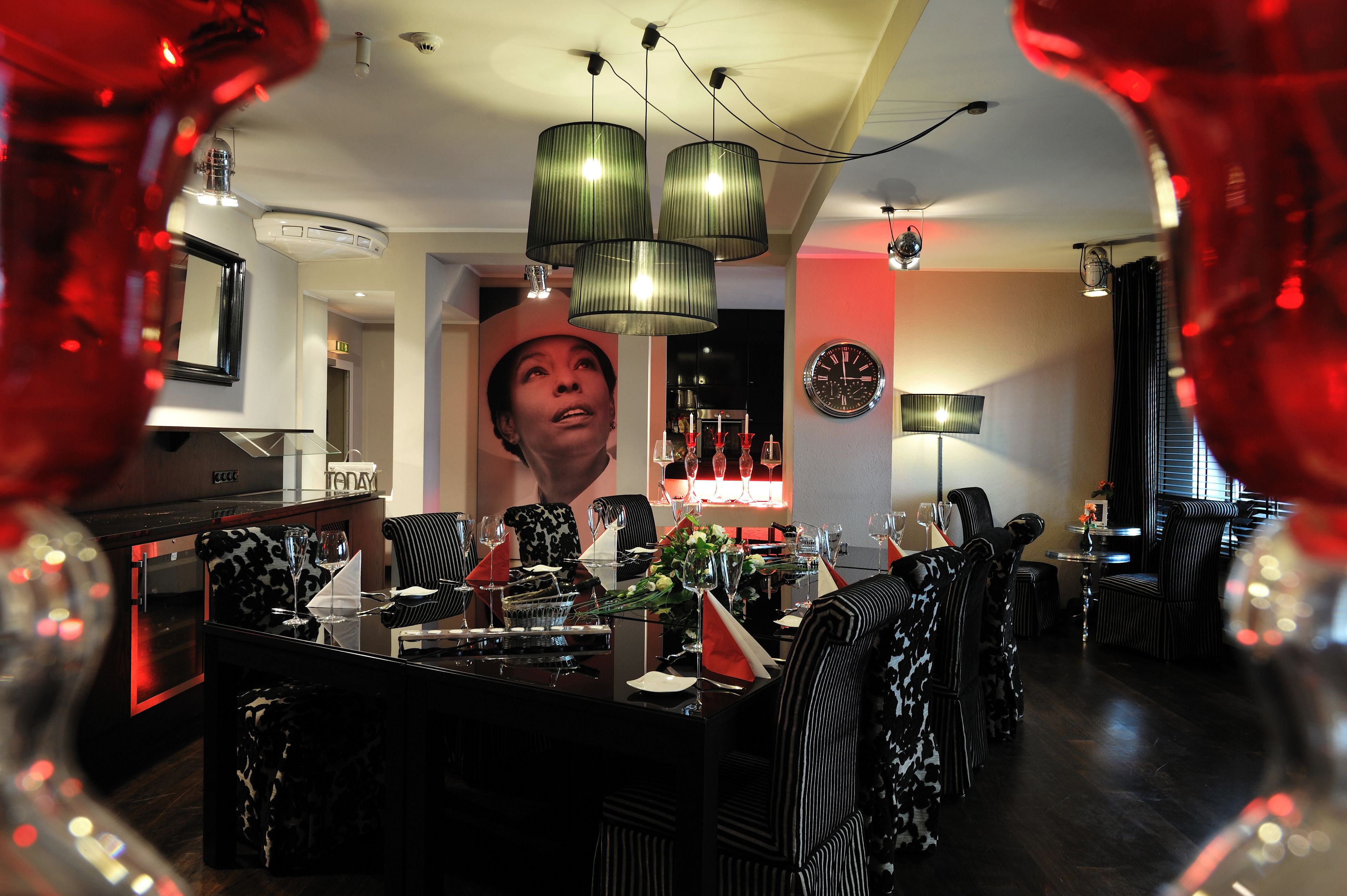 A dining area with a bar, black and white striped chairs, and a large clock on the wall.