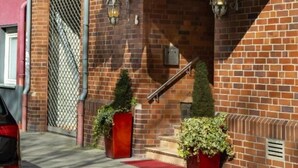 A hotel entrance with a red sign reading "Hotel Lesting," flags, and a brick facade. - Hotel Lessing (Düsseldorf)