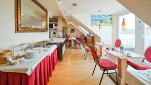 A restaurant with a long counter, red chairs, and a large mirror. - Hotel Lessing (Düsseldorf)