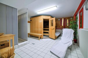 A sauna room with a bench, a wooden cabinet, and a bench with a towel.