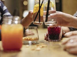 Un grupo de personas sosteniendo vasos con pajitas, un tarro con una bebida roja y un vaso con una bebida amarilla.