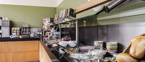 A buffet setup with various food items, a coffee machine, and a granini box.