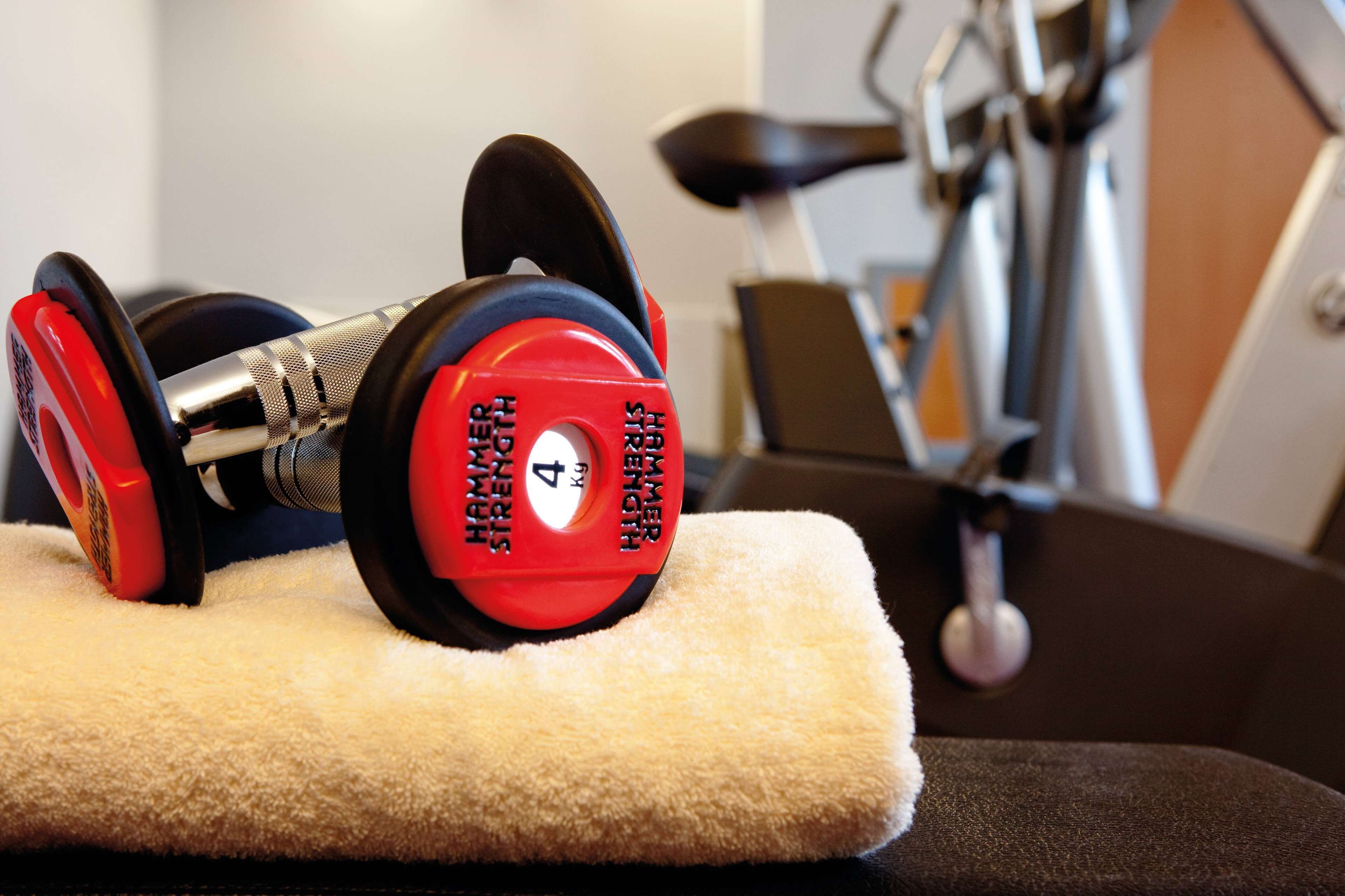 A red and black dumbbell with a weight of 4 kg on a white towel.
