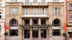 Un edificio histórico con un estilo arquitectónico clásico, que presenta una entrada central con alfombra roja, ventanas grandes y balcones.