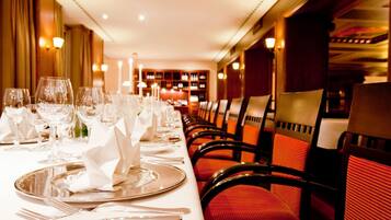 A long dining table set with multiple place settings, including plates, cutlery, and glasses.