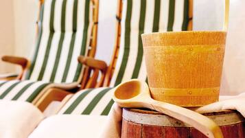 Two striped lounge chairs with a wooden bucket and a wooden spoon on a wooden stool.