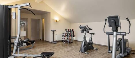 A home gym with a bench press, elliptical, and weight rack.