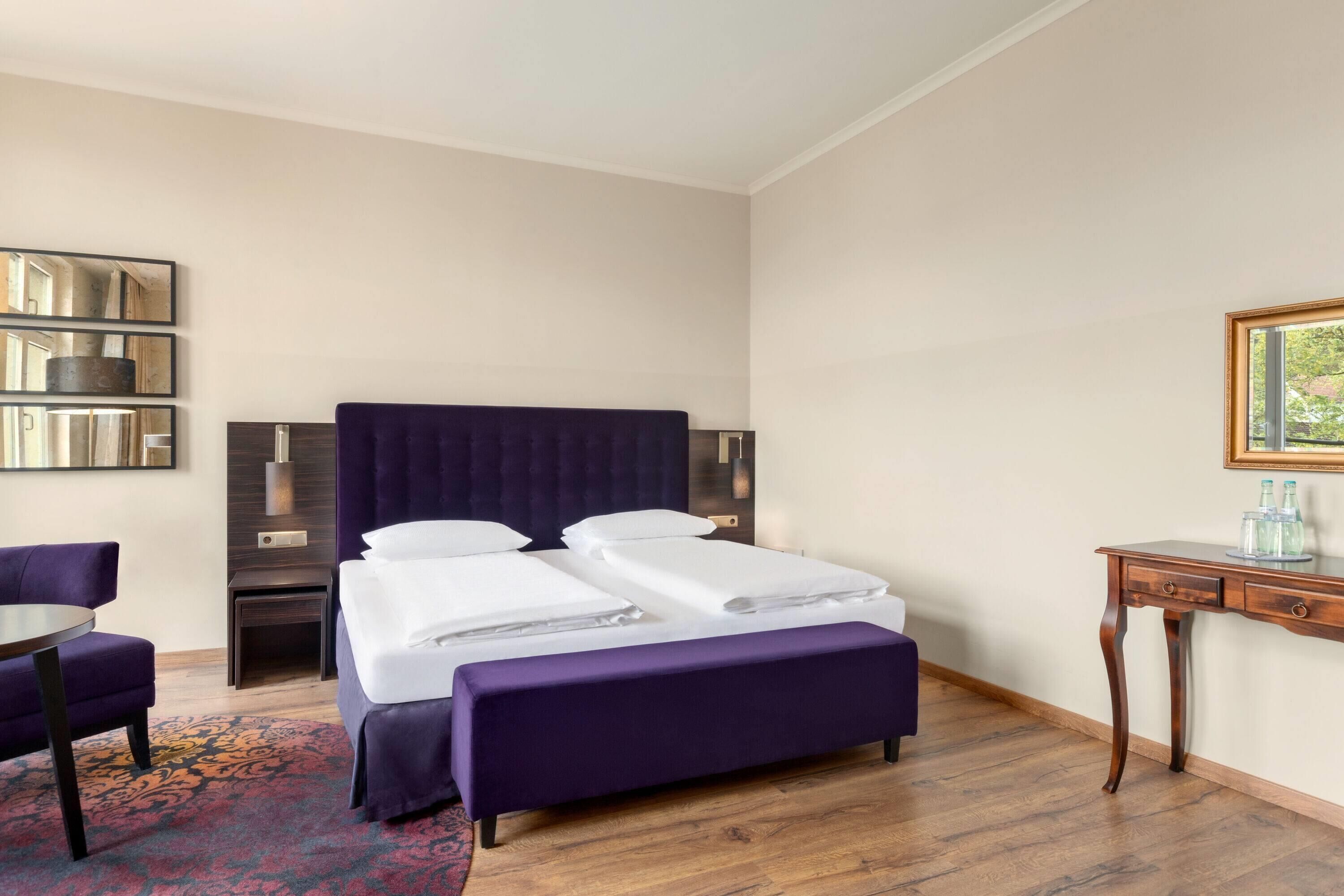 Ein Hotelzimmer mit Bett, Schreibtisch, Stuhl und Spiegel.