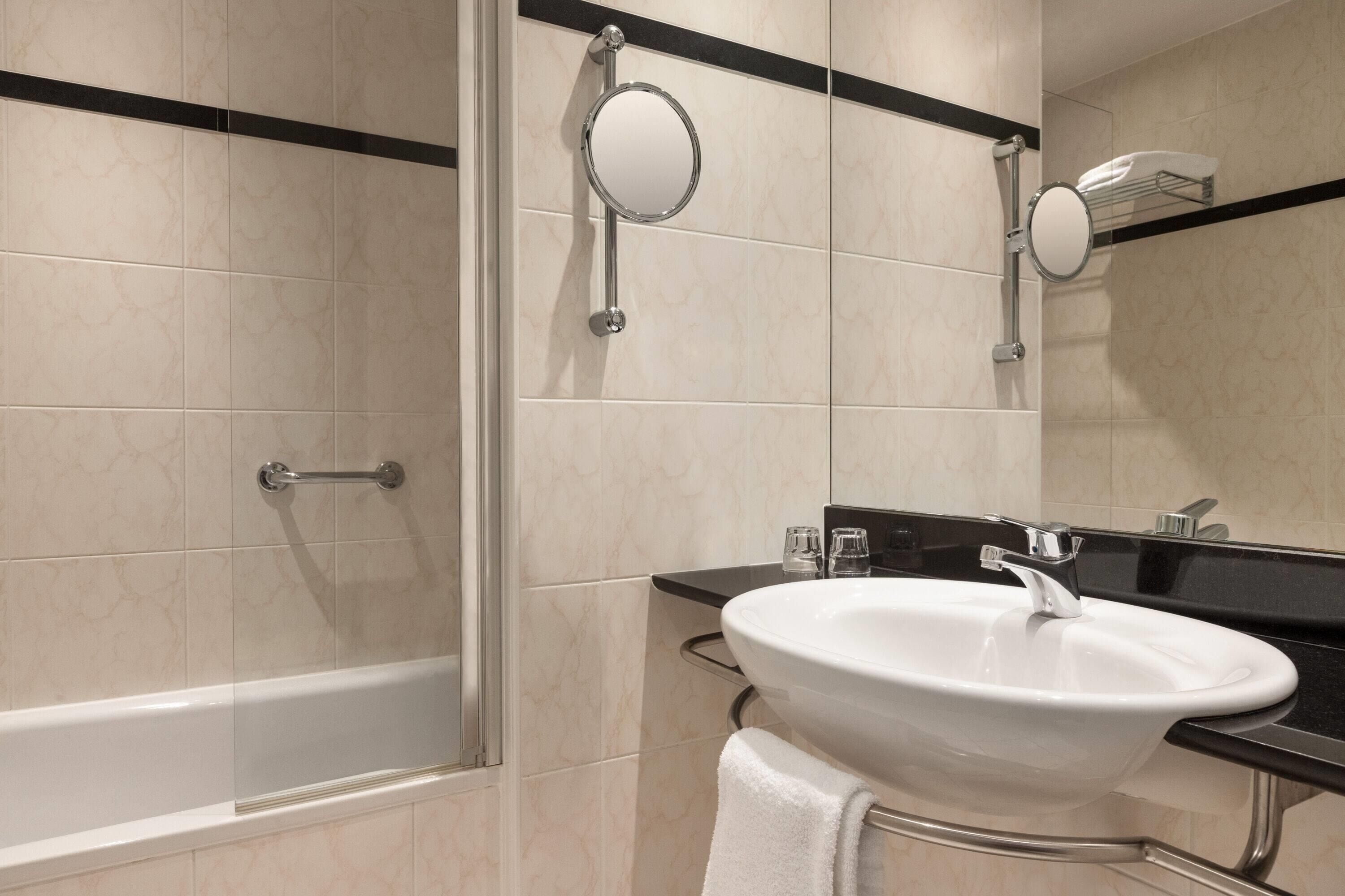 A modern bathroom with a bathtub, a sink, and a mirror.