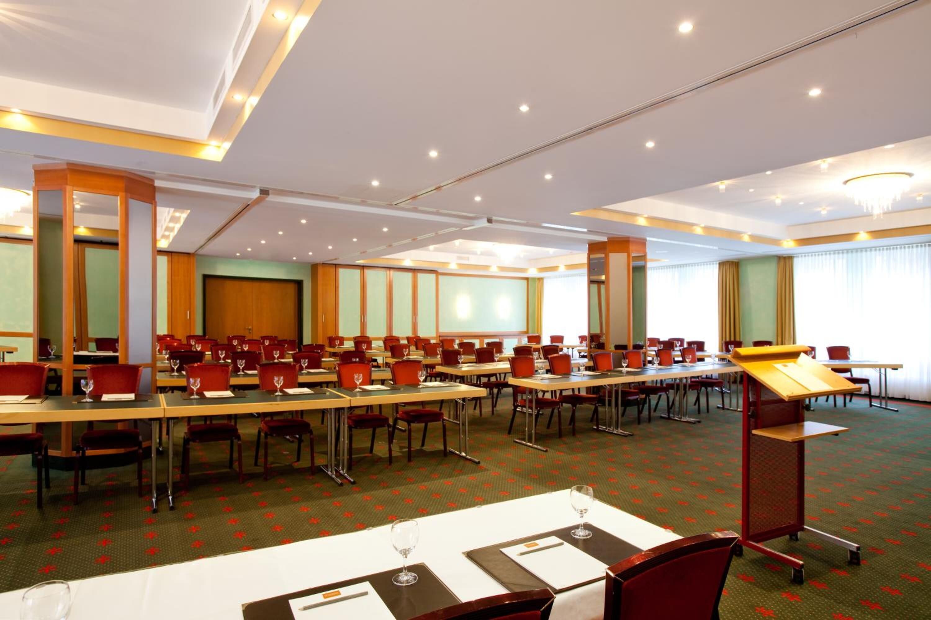 A conference room with multiple tables and chairs, equipped with nameplates and wine glasses.
