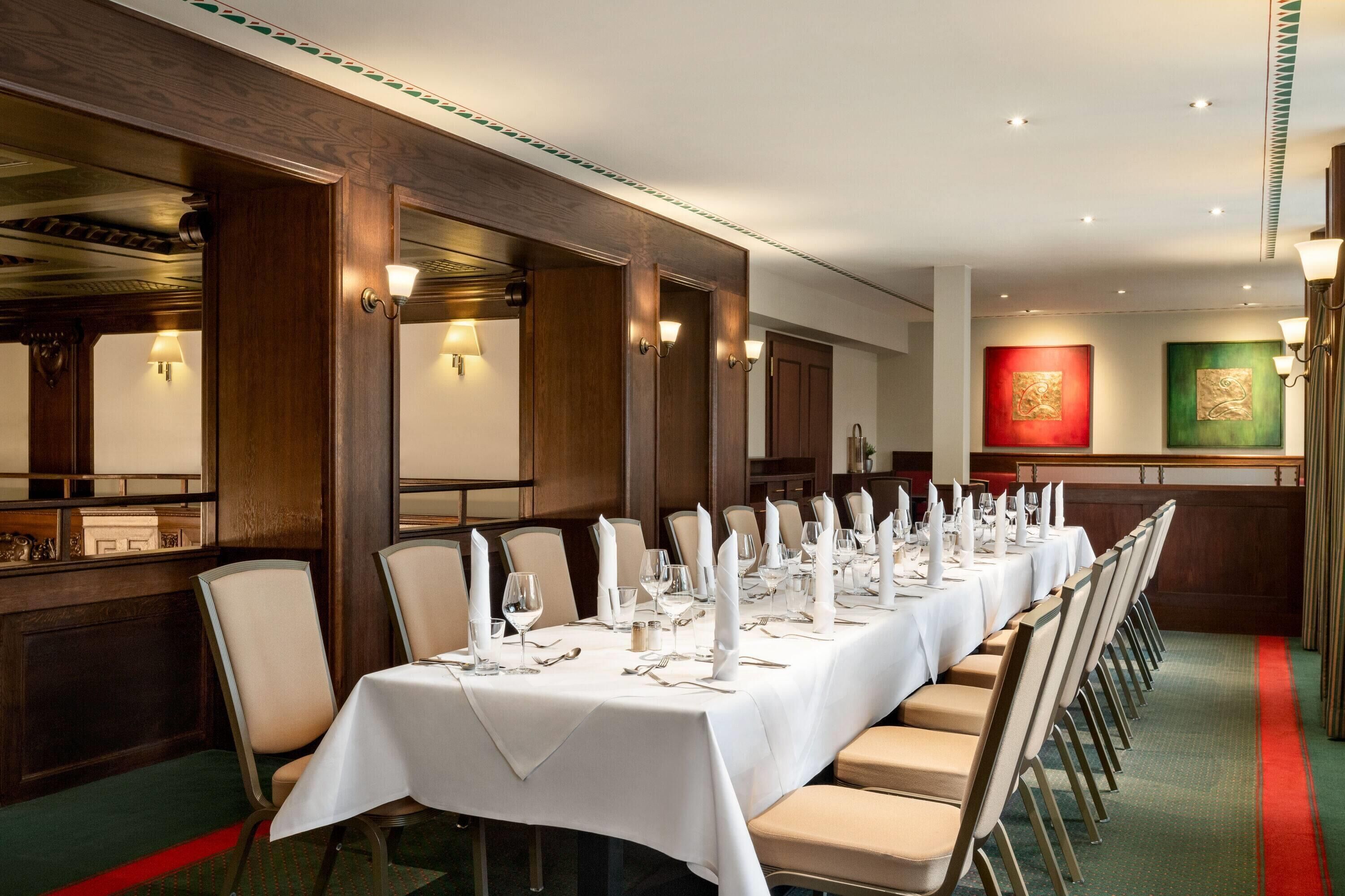 A long dining table set for a formal meal, with chairs aligned on both sides.