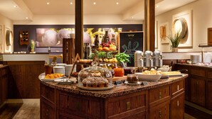 Un bufé con gran variedad de alimentos, un televisor de pantalla plana grande y una pared decorativa con un espejo y plantas.