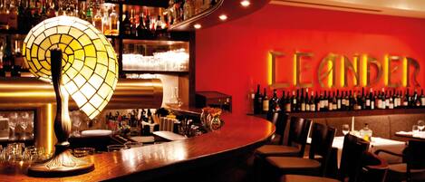 Una zona de bar con una mesa redonda, sillas y una pared con botellas.
