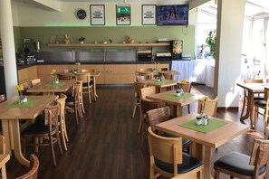 Diners enjoy meals in a cozy space with tables, chairs, and decorative touches.