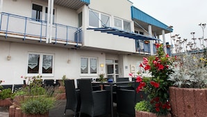 A two-story building with a balcony, outdoor seating area with chairs and tables, and potted plants. - Good Morning Erfurt (Erfurt)