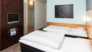 A hotel room with two beds, a TV, a wooden headboard, a wall art piece, and a mirror. - Good Morning Erfurt (Erfurt)