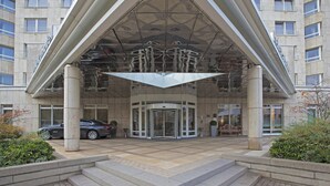 Ein Hotel mit einem Glastürschleuseingang, einem geparkten Auto davor und einer Treppe, die zum Eingang führt.