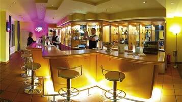 Un espace bar doté d’un comptoir incurvé, de tabourets de bar et d’un barman.