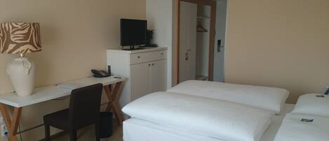 Una habitación de hotel con escritorio, silla, dos camas, televisor y armario.
