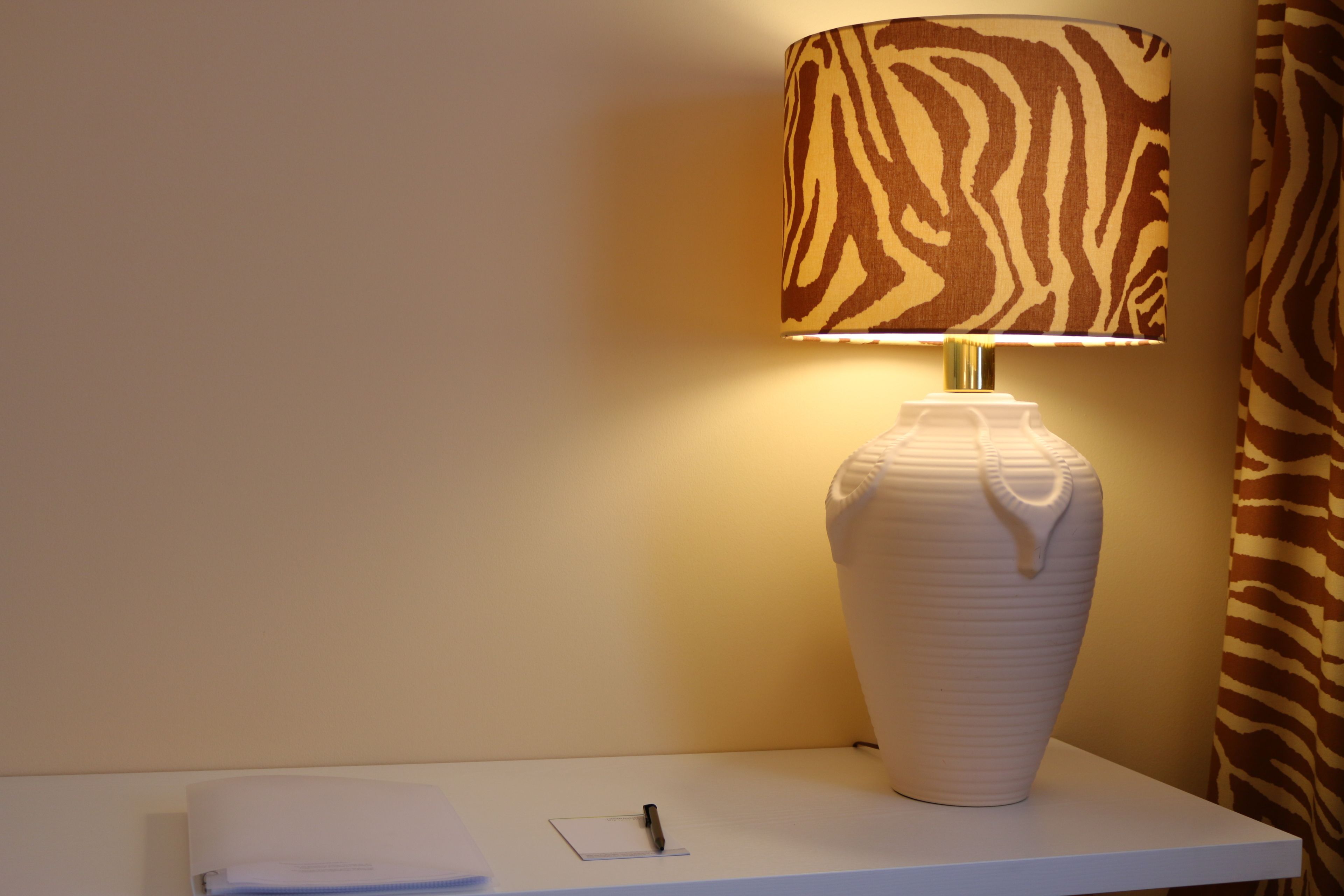 Uma mesa branca com um vaso branco e uma caneta.