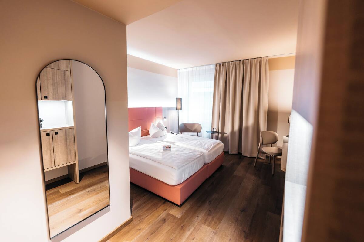 Una habitación de hotel moderna con una cama grande, un escritorio, una silla y un armario.