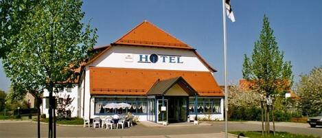 A hotel with a red roof and a sign that reads "HOTEL" in the center.