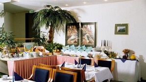 A dining area with tables set for a meal, a large plant, and framed artwork on the wall. - Apart Hotel Gera (Gera)
