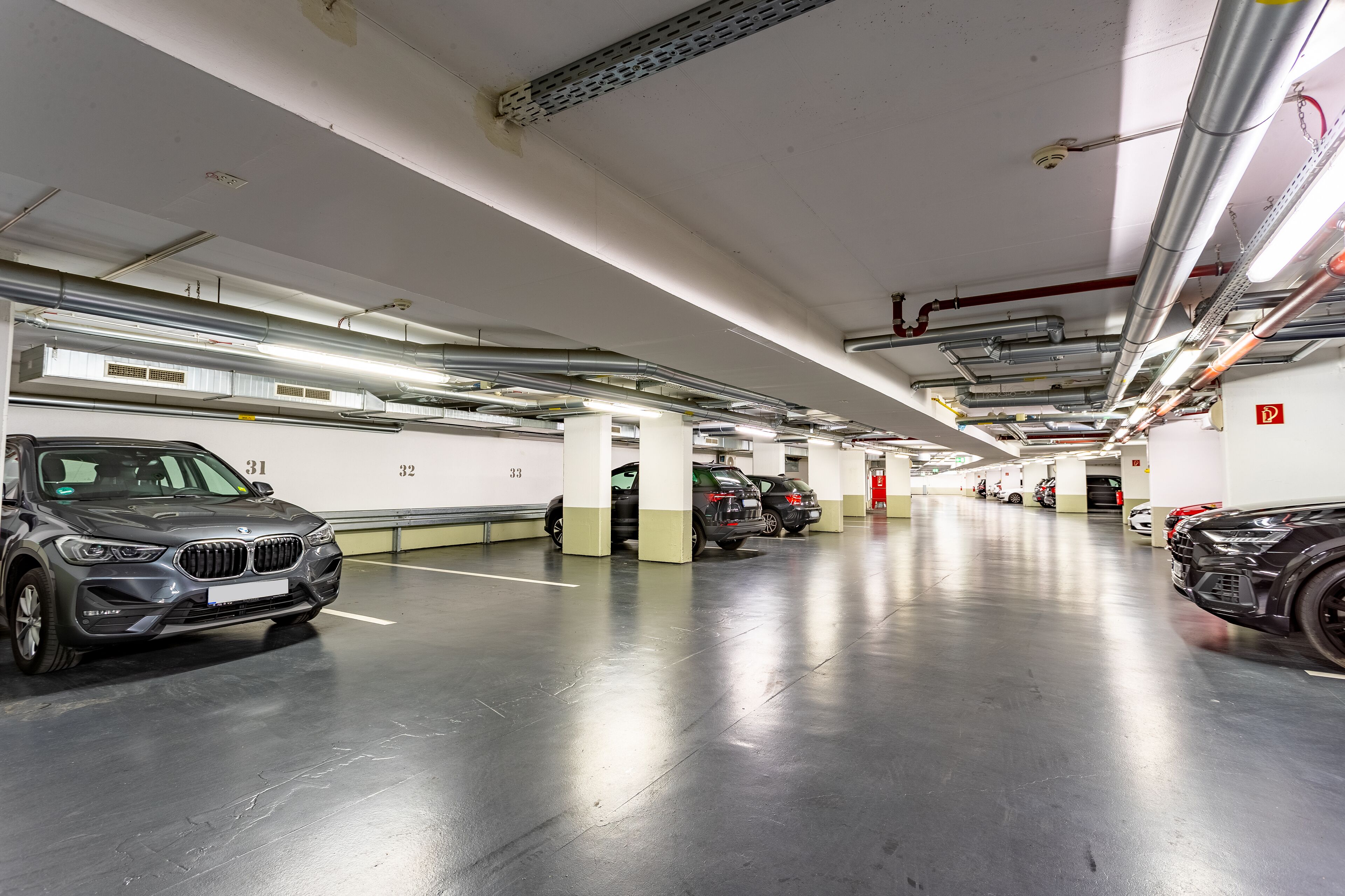 Un estacionamiento de varios niveles con varios autos estacionados, incluyendo un BMW.