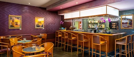 A bar area with wooden chairs and tables, a bar counter with a wine rack, and framed pictures on the wall.